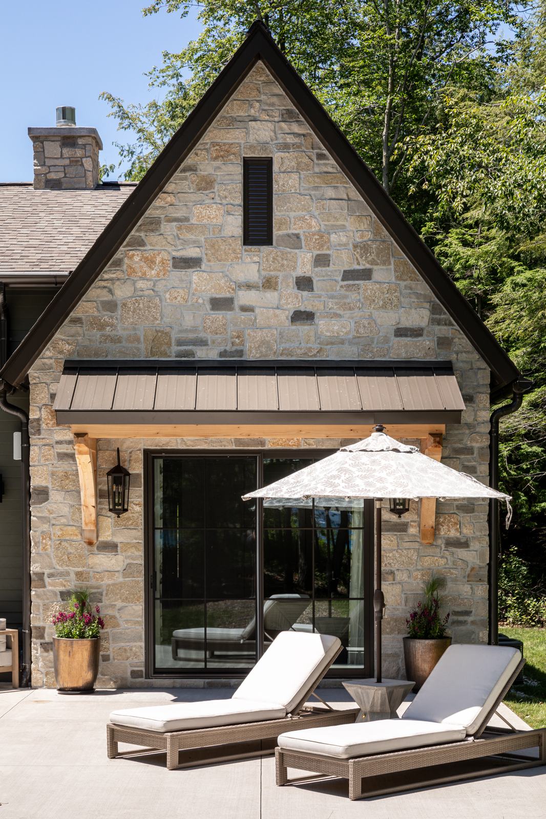 Stone cottage exterior with a patio and lounge chairs