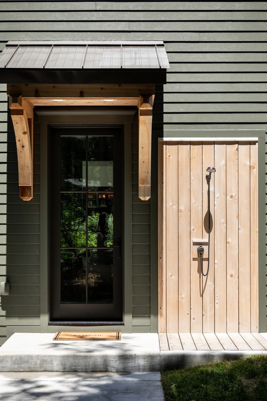Entry door with timber canopy and board siding