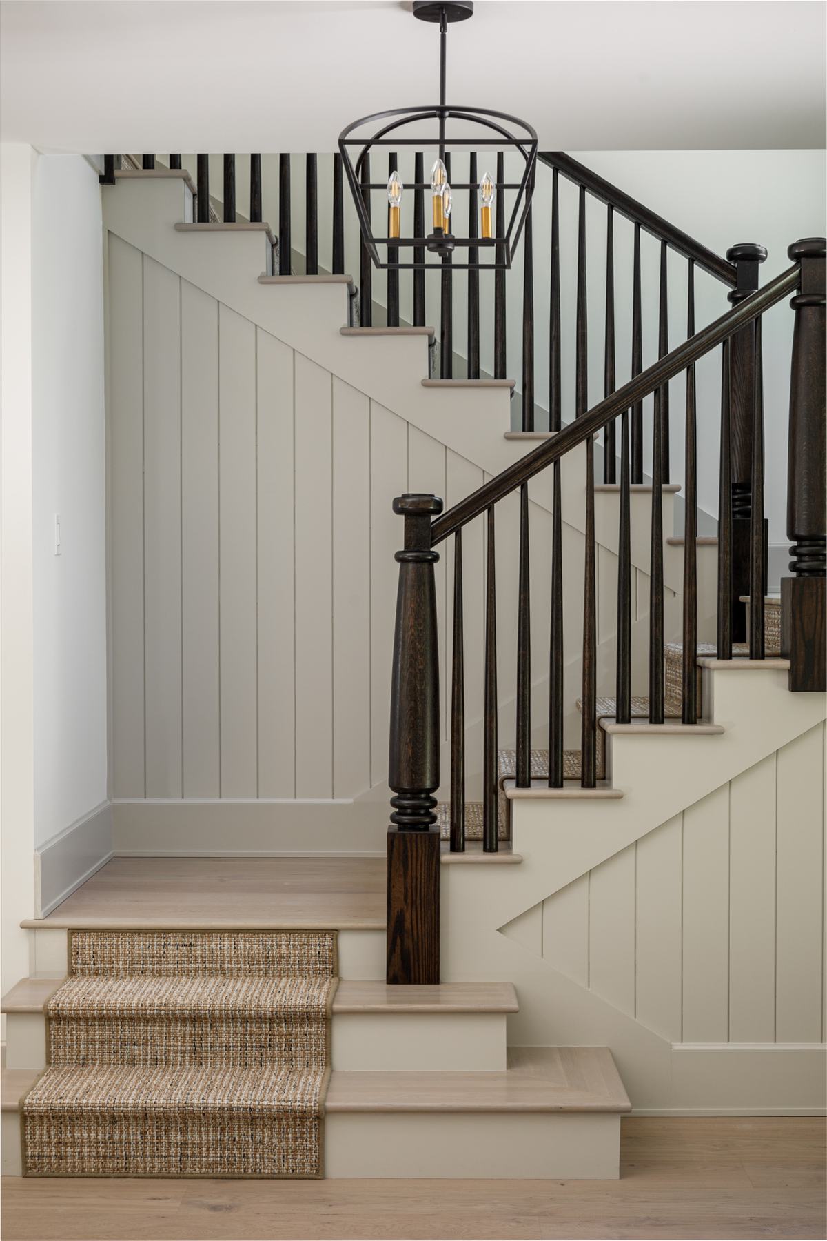 Staircase with dark railings and board-and-batten walls